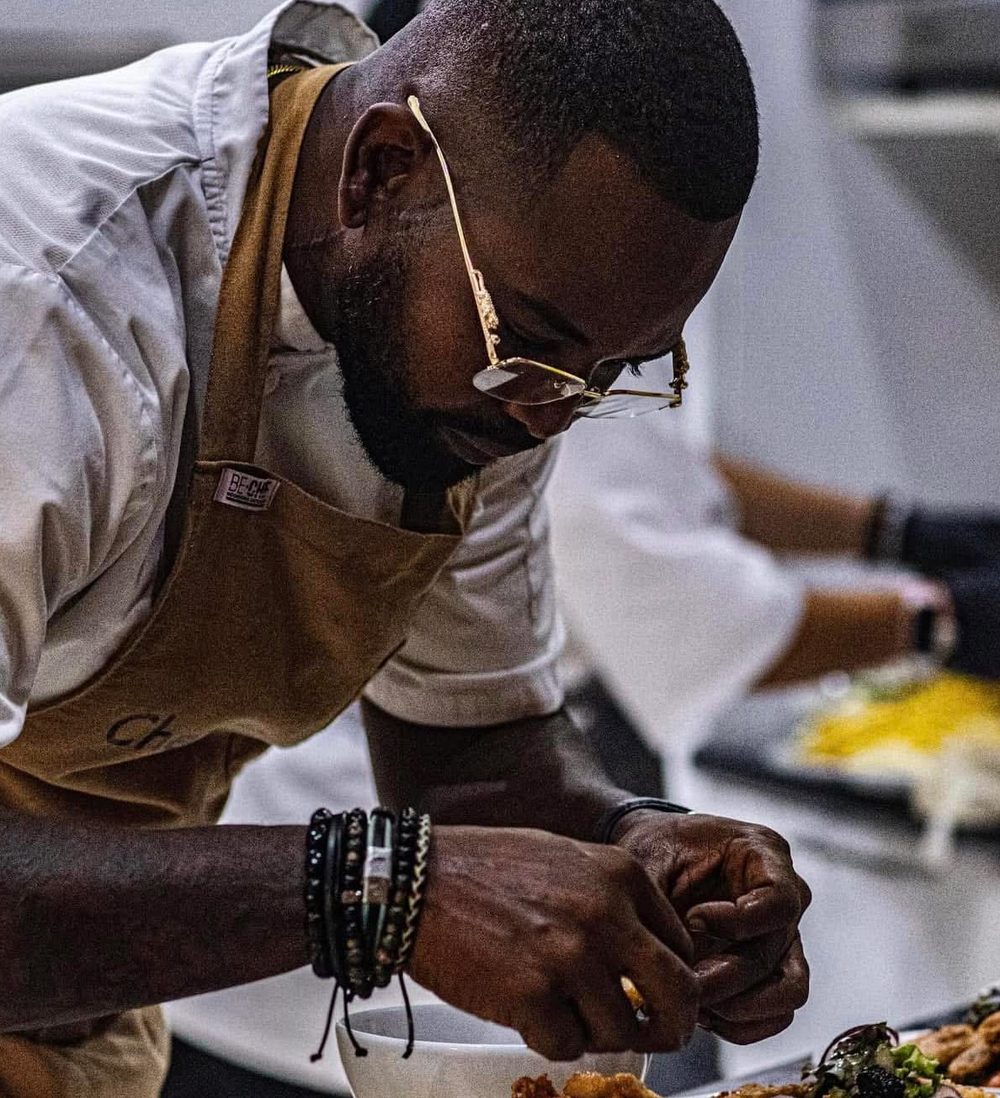 Chef Moisés Carvajal leaning over a plate, finishing a dish by hand